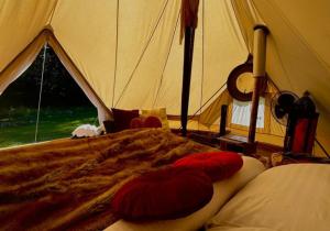 Kanimbia Luxury Glamping في Obi Obi: سرير في خيمة عليها وسادتين حمراء