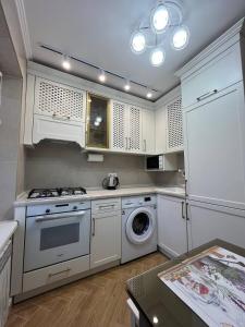 a kitchen with a stove and a washing machine at Loading Apartments in Chernivtsi