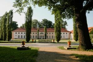 Un gran edificio blanco con árboles delante. en Natur Erleben Im Ländlichen Gästehaus An Der Havel, en Paretz