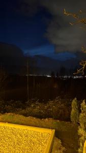 Romantic Chalet with Jacuzzi & Sauna 2- Trebević near Sarajevo في سراييفو: مقعد أصفر في حقل ليلاً +3 صور