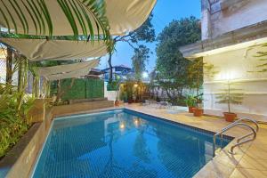 ein Swimmingpool mit Sonnenschirm neben einem Gebäude in der Unterkunft Comfort Inn Emerald in Dapoli