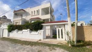 a white house with white doors and a fence at Le Paradisblanc in Kelibia