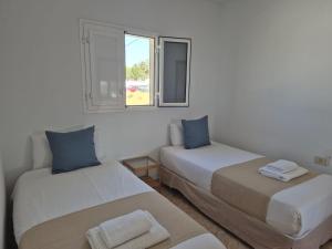 two beds in a white room with a window at Sabbia Suites Casa Vera in Teguise