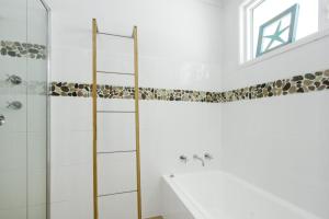 a white bathroom with a shower and a sink at Sticks by the Sea - pet-friendly coastal home in Manyana +16 photos