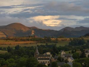 una città in una valle con montagne sullo sfondo di Entre Dômes et Sancy - Le moderne a Perpezat