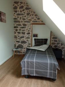 una camera da letto con un letto e un muro di pietra di Entre Dômes et Sancy - Le moderne a Perpezat