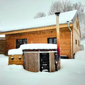 een gebouw bedekt met sneeuw met een paal bij Le bain nordique du lynx boréal in Entre-Deux-Monts