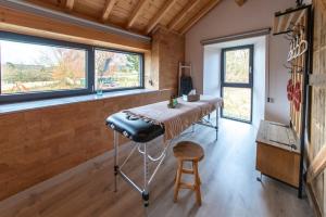 a room with a table with a stool and windows at L'école Buissonnière - Suite Bien-être 2 personnes in Vielsalm