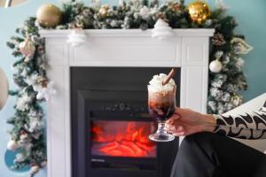 a person holding a drink in front of a fireplace at Caprioara Spa&Wellness Resort in Covasna +122 photos