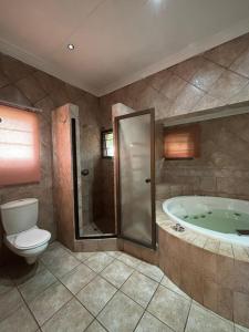 a bathroom with a tub and a toilet and a shower at Spacious 7 bedroom house with pool and jacuzzi in Johannesburg