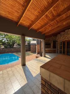 a patio with a wooden pergola and a swimming pool at Spacious 7 bedroom house with pool and jacuzzi in Johannesburg