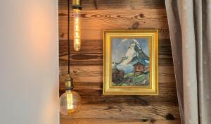 a painting on a wooden wall with lights and a lamp at Mattertal Lodge in Embd