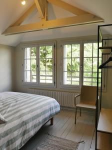 a bedroom with a bed and a chair and windows at LE CEDRE Maison bord de LOIRE 4 in Muides-sur-Loire