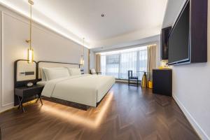 a bedroom with a white bed and a large window at G Mansion Hotel in Kunming