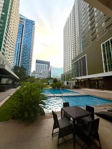 Cebu Minimaluxe Studio Condotel By Go2 Stays في مدينة سيبو: مسبح وكراسي وطاولة وبعض المباني