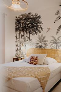 a bedroom with a bed with a mural of palm trees at Les Villas Mandju in Sainte-Rose +83 photos