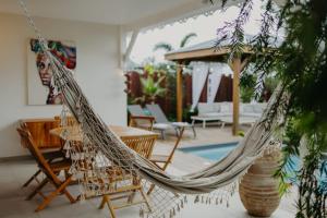 a hammock in a patio with a table and chairs at Les Villas Mandju in Sainte-Rose