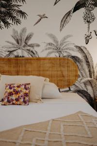 a bedroom with a bed with plants on the wall at Les Villas Mandju in Sainte-Rose