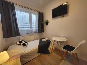 Kleines Zimmer mit einem Bett, einem Tisch und einem TV. in der Unterkunft VESTA Apartamenty P23 in Stettin