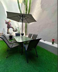 a table and chairs with an umbrella on a green floor at Kamya cottage in New Delhi