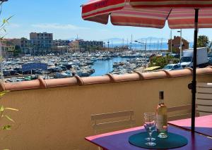 een fles wijn en een glas op een tafel met een jachthaven bij Tokelau - Vue Mer in Sausset-les-Pins