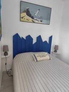 a bed with a blue headboard in a bedroom at Appartement cosy à Damgan avec vue mer 32 m² in Damgan