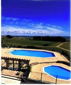 a pair of swimming pools with the ocean in the background at Appartement cosy à Damgan avec vue mer 32 m² in Damgan