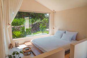 ein Schlafzimmer mit einem Bett und einem großen Fenster in der Unterkunft Gamsanchagyung in Seogwipo