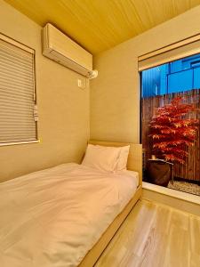 a small bed in a room with a window at NEW Hotel Komugi Skytree - modern Japanese-style guesthouse near Asakusa & Skytree 3mins, whole house rental perfect for large groups up to 14pax in Tokyo +27 photos