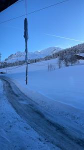une route enneigée avec un poteau sur le côté dans l'établissement CHARMIEUX appartement en chalet typique, au Grand-Bornand 24 autres photos