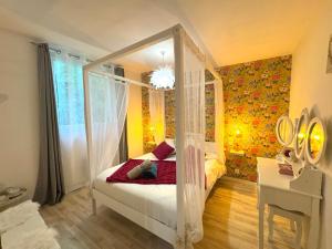 Un dormitorio con una cama con dosel en una habitación. en La Maison Labonnechose - Piscine chauffée - Calme - Jeux, en Notre-Dame-de-Fresnay