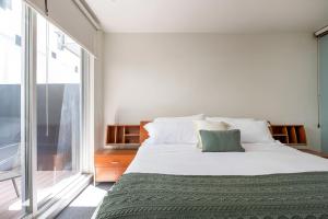 una camera da letto con un letto grande con una grande finestra di Chic 2BR Condo in Condesa steps from Parque Mexico a Città del Messico