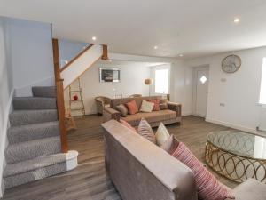 a living room with a couch and a staircase at Ty'n Lon Farm in Pwllheli