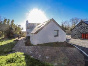 a small white house with the sun in the background at Ty'n Lon Farm in Pwllheli