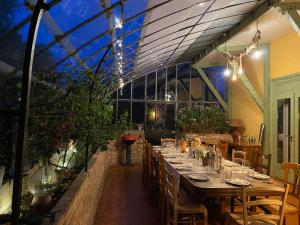 Un comedor con una mesa larga en un invernadero. en Le Baccara Lodge, véritable maison de famille avec piscine et parc, en Arengosse