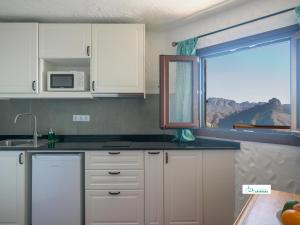 a kitchen with white cabinets and a window at Living Artenara - EARTH Adults Only in Artenara
