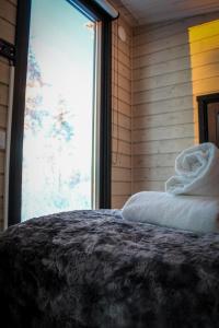 een slaapkamer met een bed met witte lakens en een raam bij Palas Experience Olkkajärvi Resort in Rovaniemi
