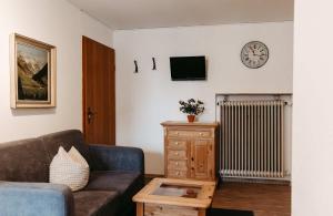 a living room with a couch and a clock on the wall at Pension Adler in Sonthofen