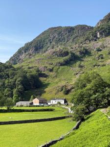 een boerderij voor een berg met een hek bij The Cottage in Borrowdale Valley