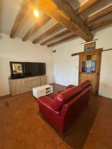a living room with a red couch and a flat screen tv at Au plaisir de l'ivoie in Le May-sur-Èvre