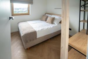a bedroom with a bed with white sheets and a window at Miło in Lubiatowo