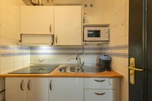 eine kleine Küche mit Spüle und Mikrowelle in der Unterkunft Conde Center Premium Suites in Sevilla + 13 Fotos