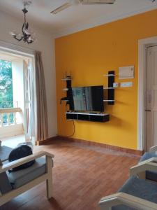 a living room with a tv on a yellow wall at 1Bhk URA Apartment Candolim in Candolim