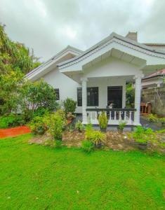 a white house with a lawn in front of it at White House Mirissa in Mirissa