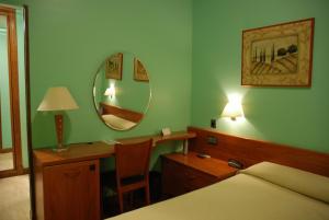1 dormitorio con cama, escritorio y espejo en Hostal Los 5 Pinos, en Madrid