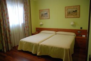 Habitación de hotel con 2 camas y ventana en Hostal Los 5 Pinos en Madrid