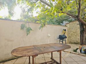 a wooden table in front of a wall at Charmante maison de village 8 personnes avec parking gratuit in Tourreilles