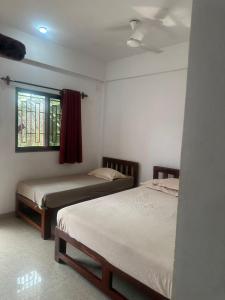 een slaapkamer met twee bedden en een raam bij Laxmi house in Arambol