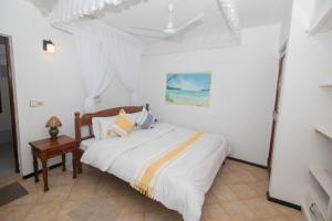 een slaapkamer met een bed met witte lakens en een tafel bij The Malindi Mansion in Malindi
