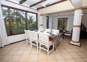 een eetkamer met een tafel, stoelen en ramen bij The Malindi Mansion in Malindi
